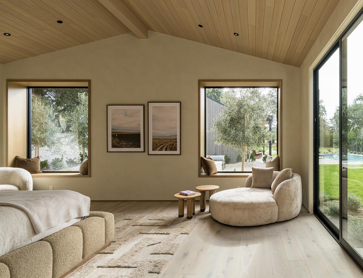 A large covered patio with multiples sets of furniture leads to a living room through a large opening.